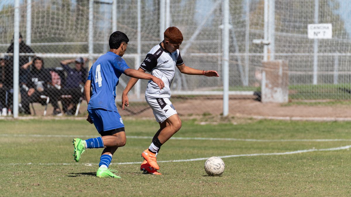 Two young soccer players competing during a match on a sunny day.