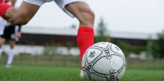 Close-up of a soccer player kicking a ball during a daytime match.