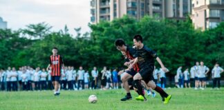 Dynamic soccer game capturing two young players in action on a grassy field surrounded by spectators.