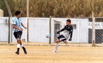 Players engaged in an amateur soccer match on a sandy field, highlighting the dynamic action of the game.