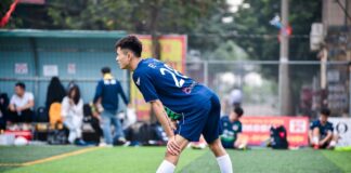 Soccer player stretching on a football field in Hanoi, Vietnam, preparing for a game.