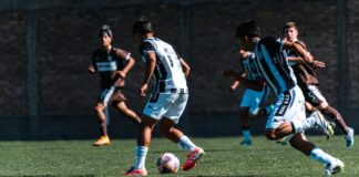 Teenage boys play competitive soccer on a sunny day, showcasing teamwork and agility.