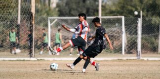 Two soccer players competing fiercely on the field during a sunny day match.