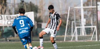 Two young players compete in a soccer match on a sunny day.