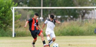 Two young soccer players in action on a grassy field during a competitive match.