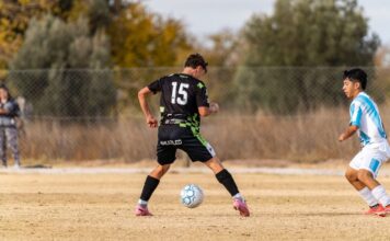 Two young soccer players in action on a sunny outdoor field during a casual game.