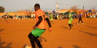 Vibrant local soccer game during sunset on a dirt field, showcasing community and athleticism.