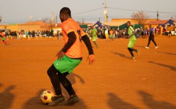 Vibrant local soccer game during sunset on a dirt field, showcasing community and athleticism.