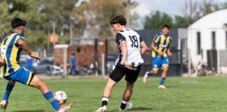 Dynamic action shot of a youth soccer match during the day on a grassy field.
