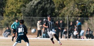 Dynamic youth soccer match taking place outdoors with engaged players and onlookers.