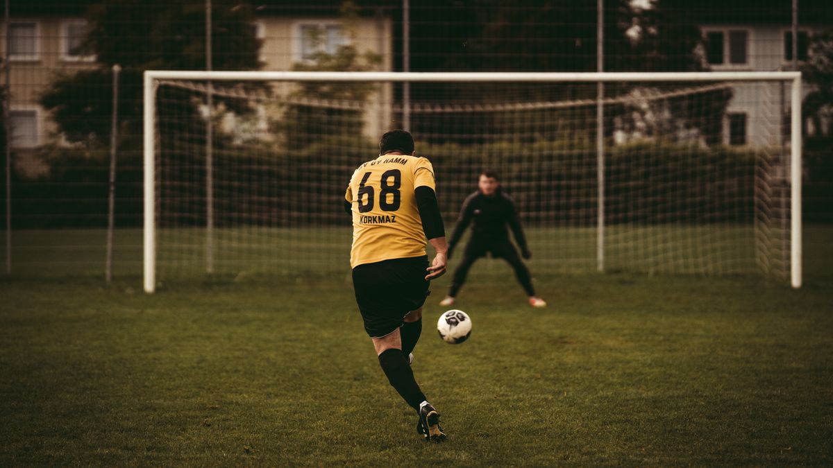 A soccer player takes a decisive penalty kick aiming to score against the goalkeeper. A soccer player takes a decisive penalty kick aiming to score against the goalkeeper.