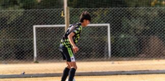 Teen soccer player in action on an outdoor field, focusing on ball control.