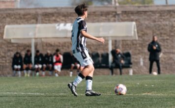 A young soccer player in action on a green field during a match.