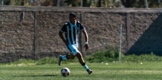 Action shot of a soccer player skillfully dribbling during a daytime match on a grassy field.