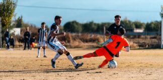 Soccer action scene with goalkeeper making a save during a competitive match.