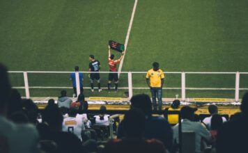Soccer player substitution during a match at a stadium with an engaged audience.