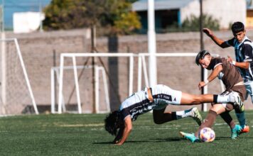 Soccer players in action during a competitive match on a sunny day.