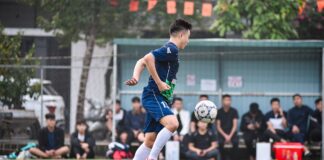 Soccer player in mid-air during a match on a Vietnam field.