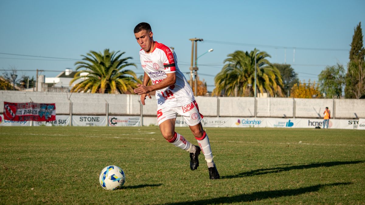 A soccer player in sportswear dribbles the ball on an outdoor field during a daytime match. A soccer player in sportswear dribbles the ball on an outdoor field during a daytime match.