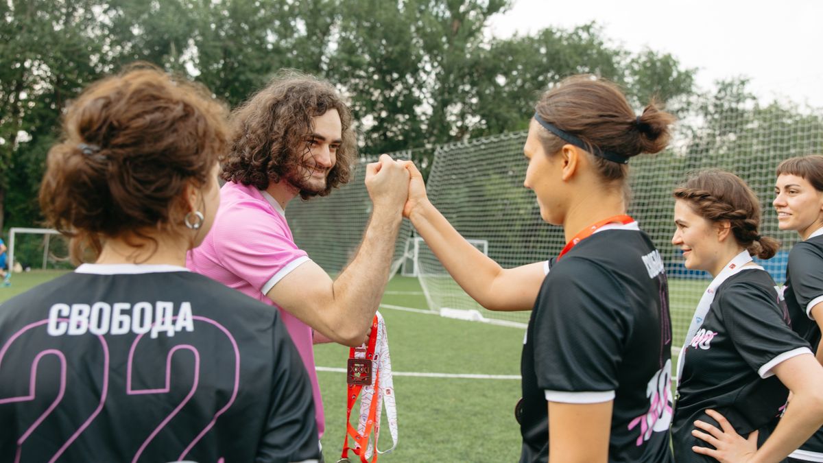 Soccer team celebrating victory on field with coach, exchanging fist bumps and medals. Soccer team celebrating victory on field with coach, exchanging fist bumps and medals.