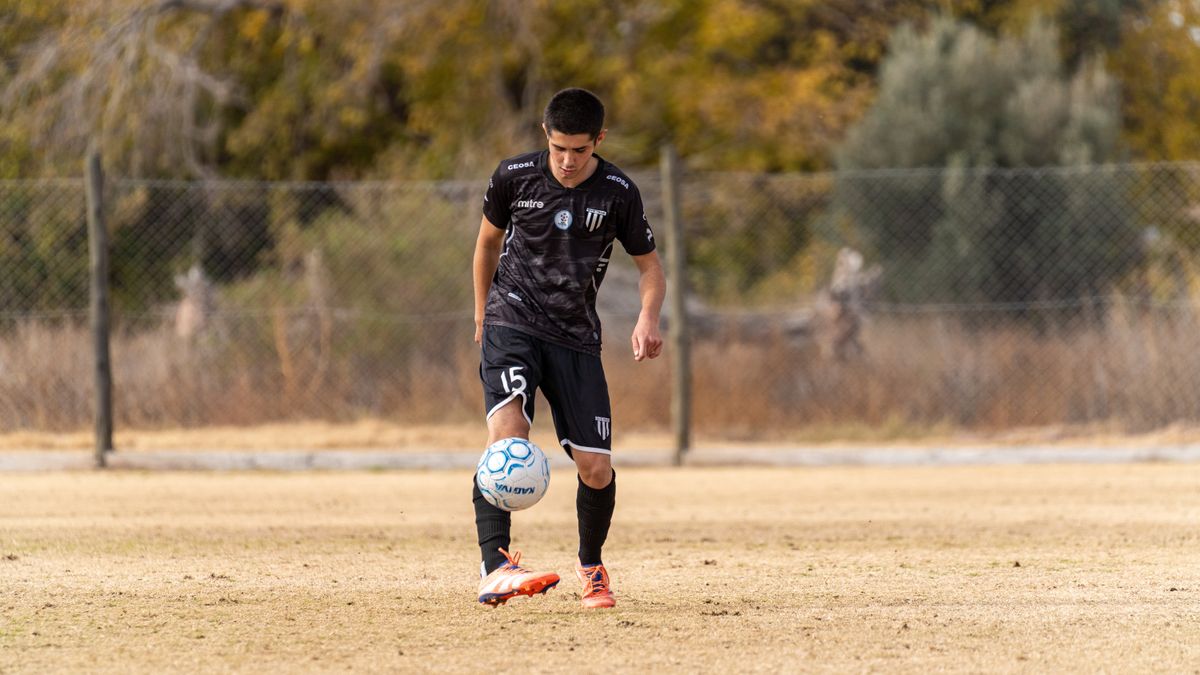 Teen soccer player wearing black jersey practices ball control on an outdoor field in autumn. Teen soccer player wearing black jersey practices ball control on an outdoor field in autumn.