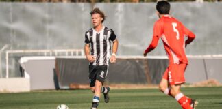 Two soccer players in action during a competitive match on a sunny day.