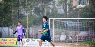 Two soccer players in action on a grassy field in Hanoi, Vietnam, showcasing teamwork and sportsmanship.