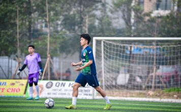 Two soccer players in action on a grassy field in Hanoi, Vietnam, showcasing teamwork and sportsmanship.