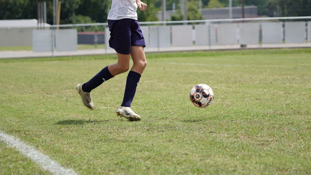 A young soccer player in action on an outdoor field during the day. A young soccer player in action on an outdoor field during the day.