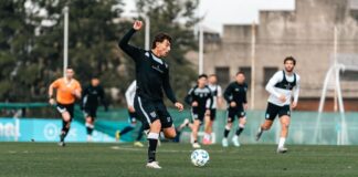 Professional soccer players in action during a training session on a field.