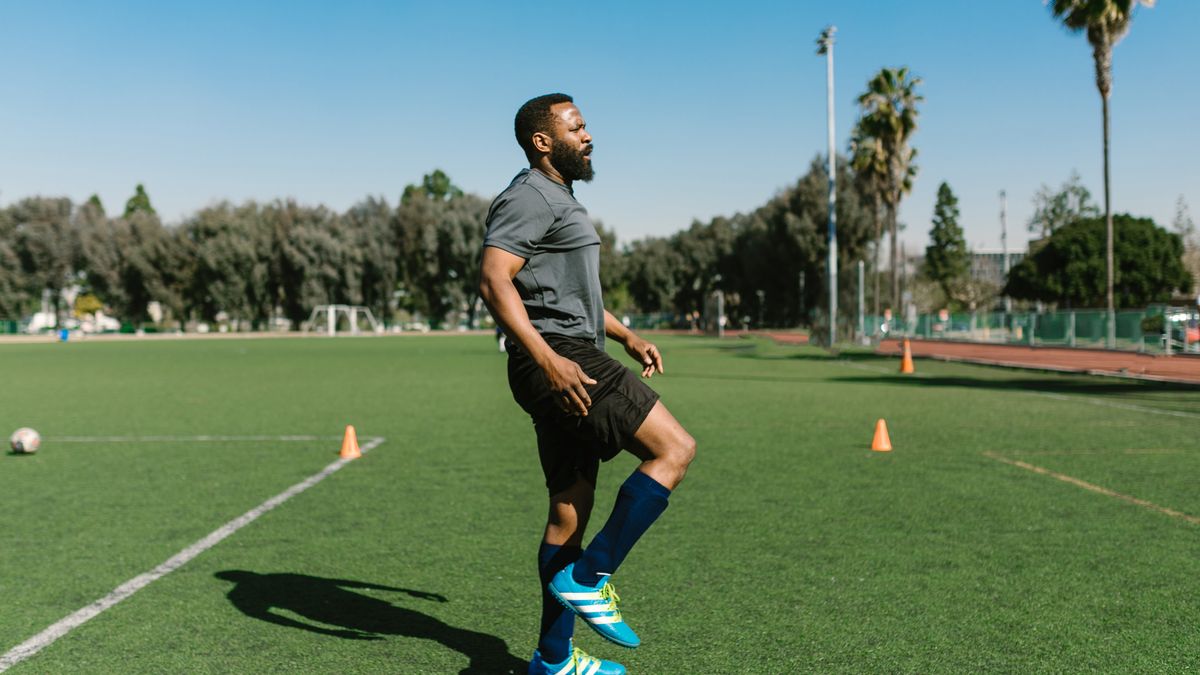 A soccer player warming up with exercises on a sunny day at an outdoor field. A soccer player warming up with exercises on a sunny day at an outdoor field.