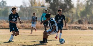 Group of boys intensely playing soccer on a sunny day outdoor field.