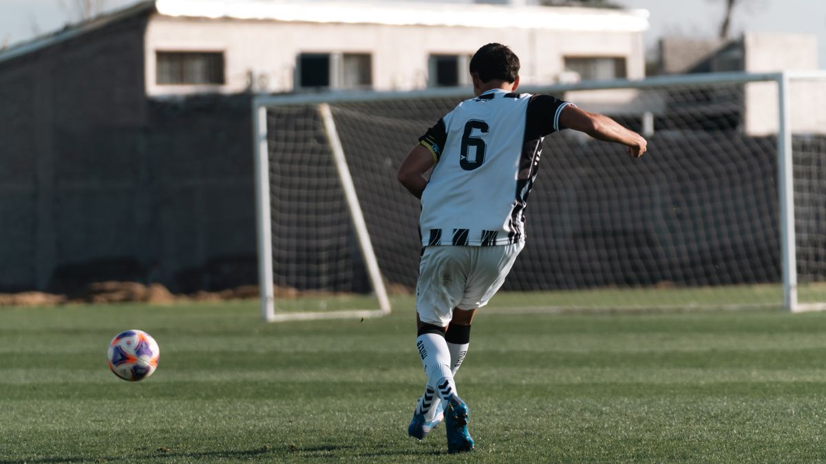 Soccer player in action, wearing number 6 jersey on a green field preparing to kick the ball. Soccer player in action, wearing number 6 jersey on a green field preparing to kick the ball.