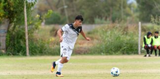 Teen soccer player dribbles the ball on the field during a competitive match.