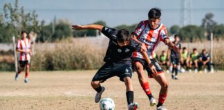 Young soccer players competing fiercely during a sunny day match on an outdoor field.