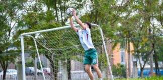A soccer goalkeeper makes a dynamic save outdoors in Hà Nội, Việt Nam.