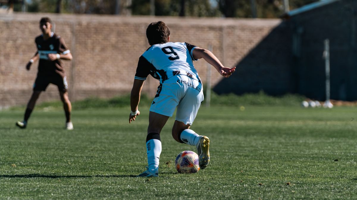 Soccer player dribbles during a match on a sunlit outdoor field with dynamic motion. Soccer player dribbles during a match on a sunlit outdoor field with dynamic motion.