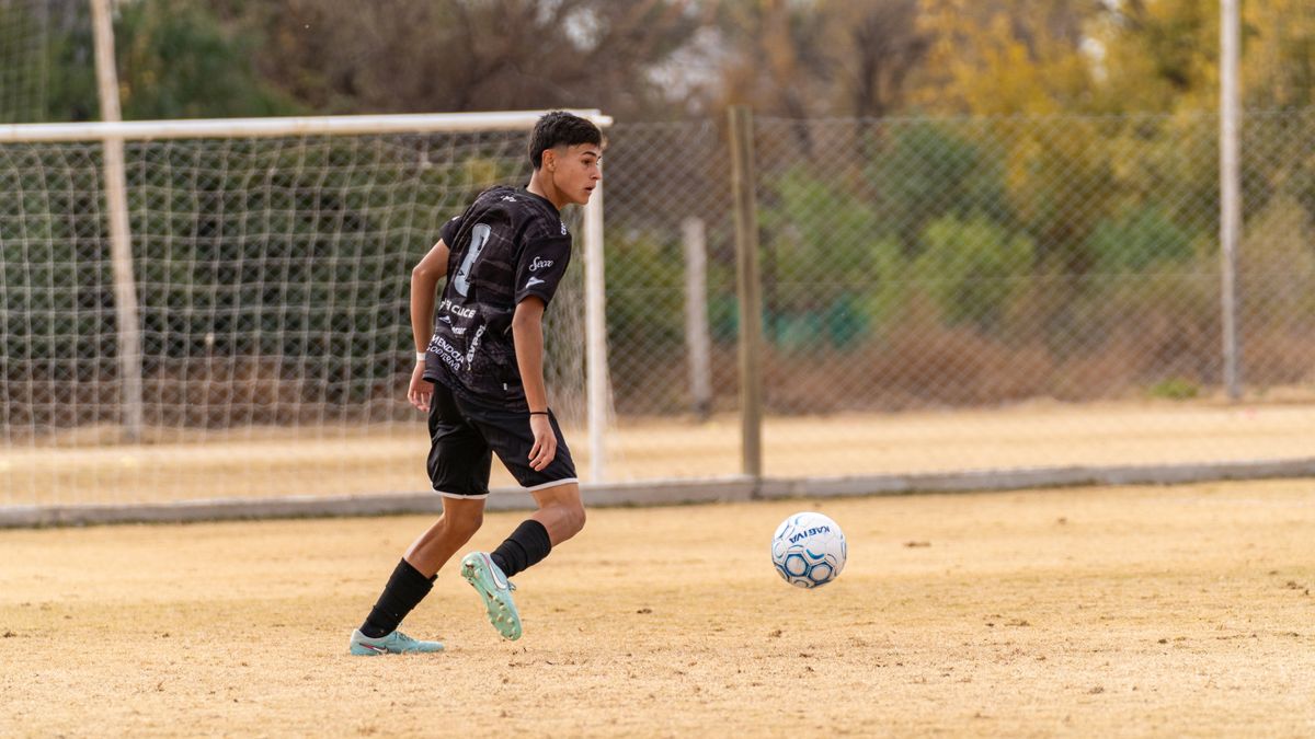 Young soccer player in action, dribbling a ball on a grass field during a game. Young soccer player in action, dribbling a ball on a grass field during a game.