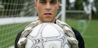 Focused soccer goalkeeper holding the ball confidently on the field.