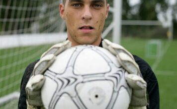 Focused soccer goalkeeper holding the ball confidently on the field.