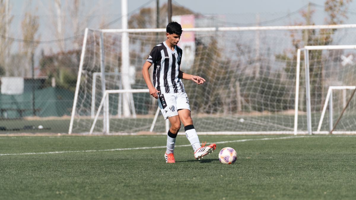 A teenage soccer player dribbles the ball on an outdoor football field during the day. A teenage soccer player dribbles the ball on an outdoor football field during the day.