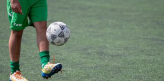 Football player practices juggling skills on a grass field. Action sports scene.