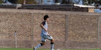 A soccer player dribbling the ball on an outdoor field during a game.