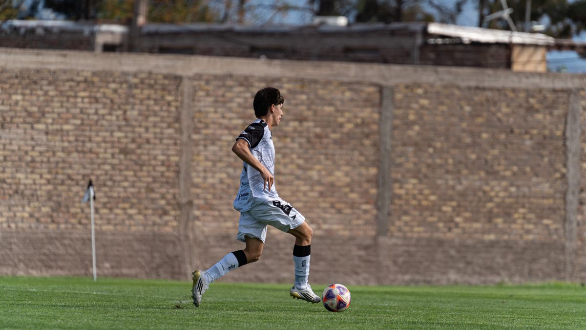 A soccer player dribbling the ball on an outdoor field during a game. A soccer player dribbling the ball on an outdoor field during a game.