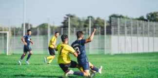 Soccer players in action during a competitive match on a sunny day outdoors.