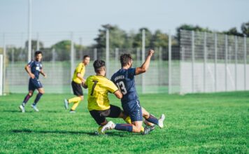 Soccer players in action during a competitive match on a sunny day outdoors.