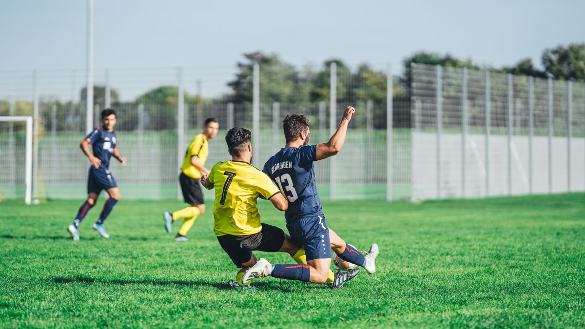 Soccer players in action during a competitive match on a sunny day outdoors. Soccer players in action during a competitive match on a sunny day outdoors.