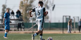 A soccer player dribbling on the field during a daytime match.
