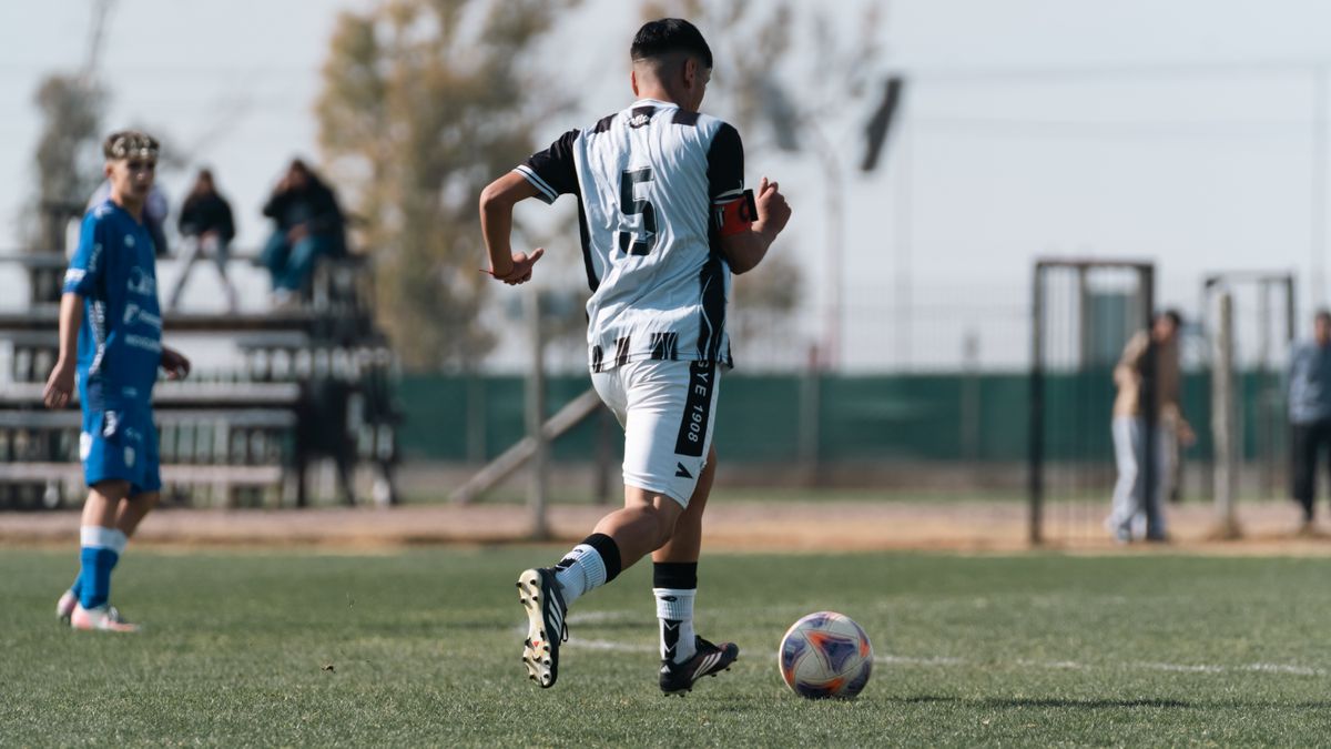 A soccer player dribbling on the field during a daytime match. A soccer player dribbling on the field during a daytime match.