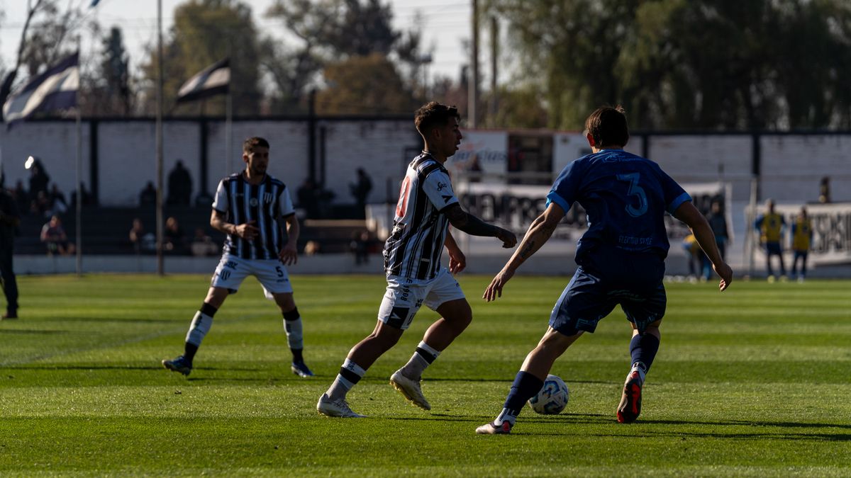 Players compete in a dynamic soccer match under clear skies on a grassy field. Players compete in a dynamic soccer match under clear skies on a grassy field.